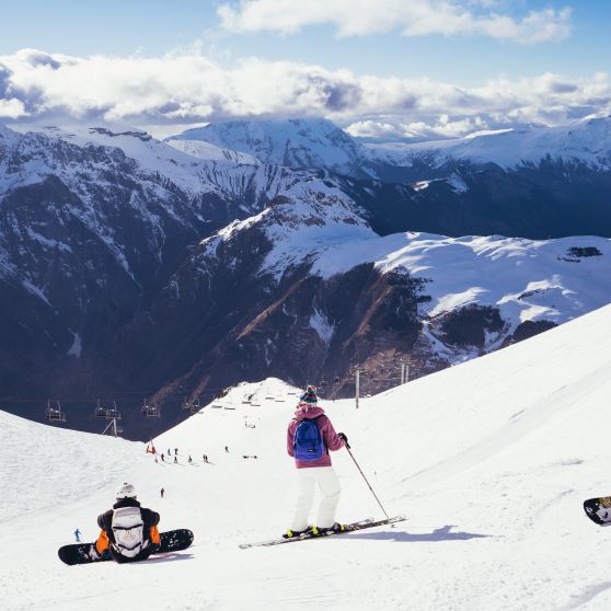 Snowboarder sitting on piste above Les Deux Alpes