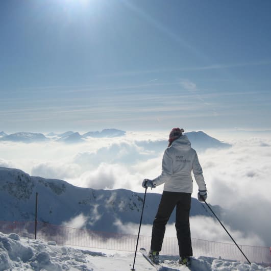 Lady on skis looking at Les Gets with clouds