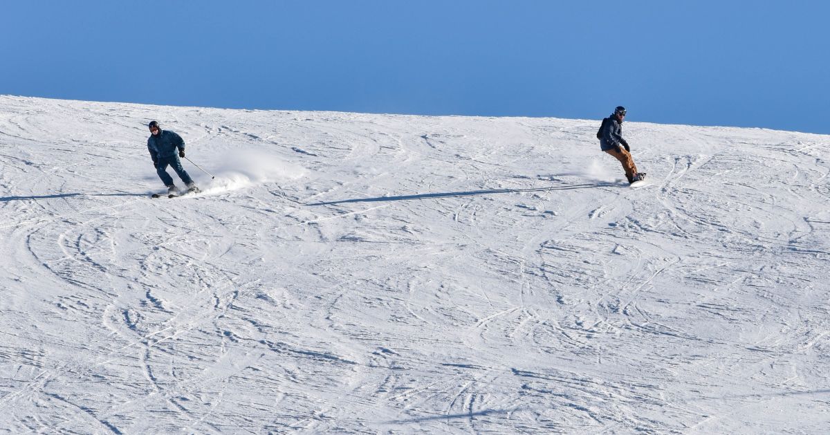 Young snowboarder sliding down snowy slope on mountain at winter